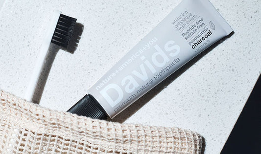 メッシュのポーチから出したDavids ホワイトニングトゥースペースト（チャコール）と黒い毛の歯ブラシ